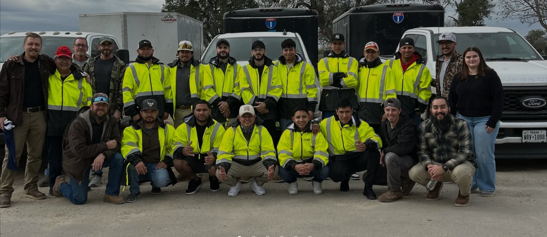 The Richter Industries crew standing together with their work trucks in New Braunfels, TX